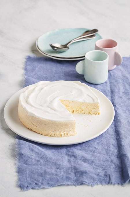 lemon cheesecake made in Instant Pot on table next to a plate and coffee mugs