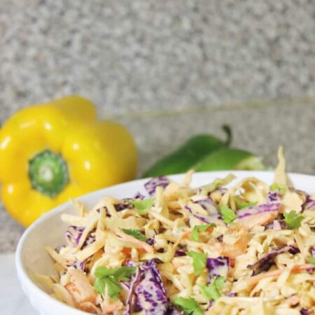 mexican slaw in a bowl with peppers behind it