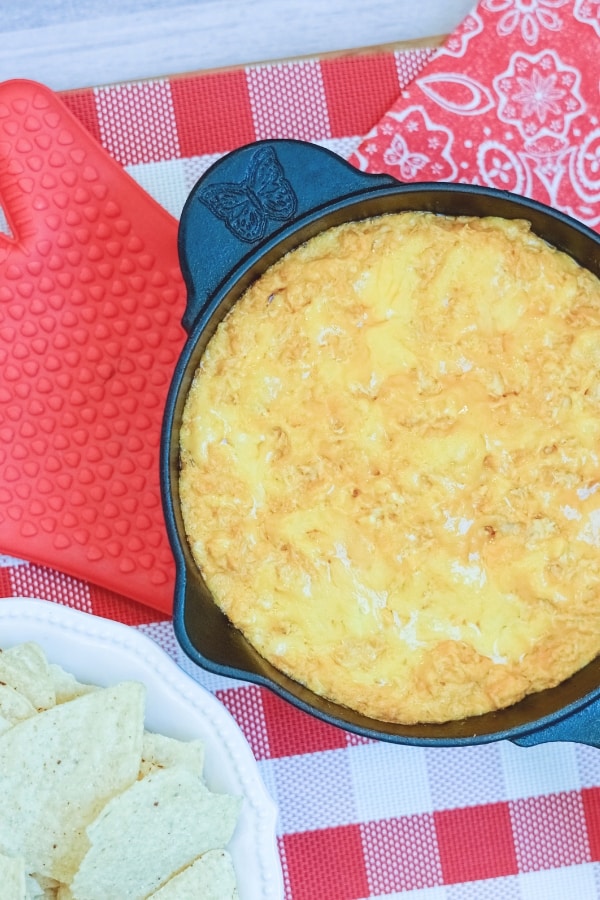 buffalo chicken dip in a pan next to bowl of chips 