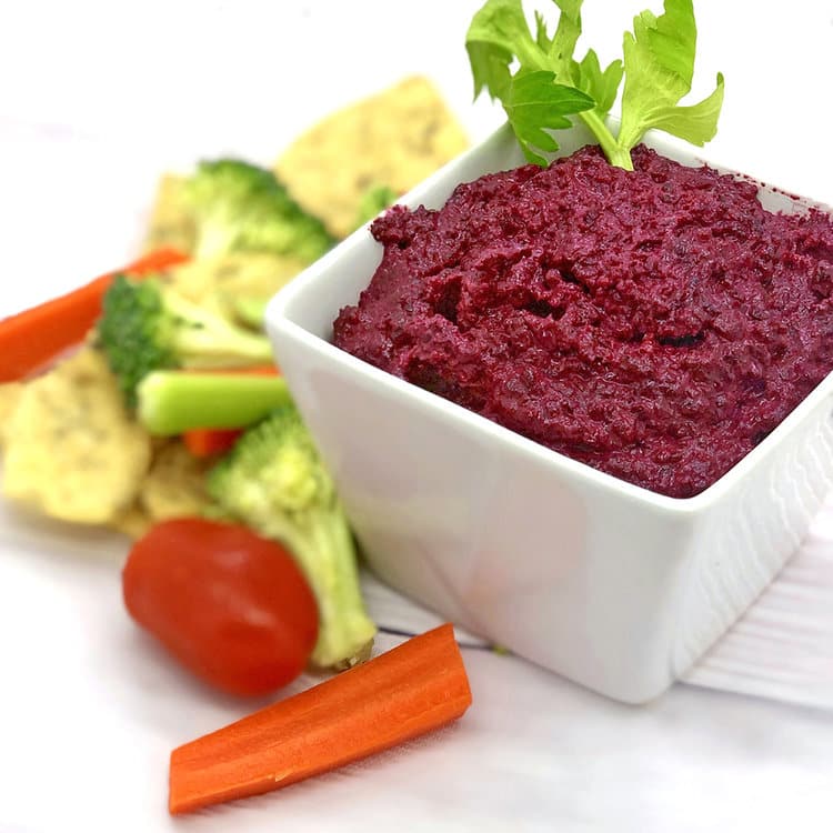 beet dip with veggies around it 