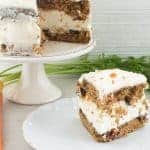 layered carrot cake on a plate with whole cake behind it