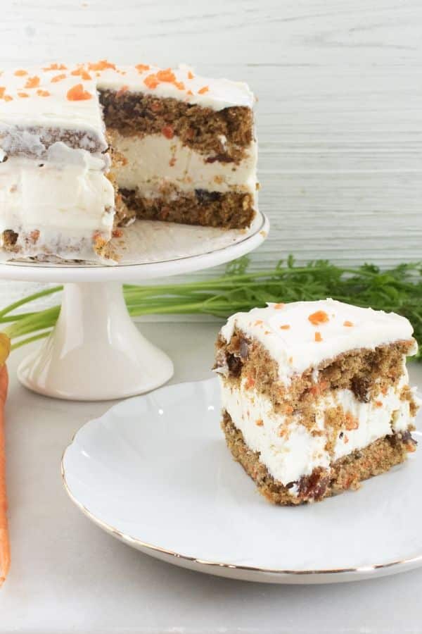 layered carrot cake on a plate with whole cake behind it