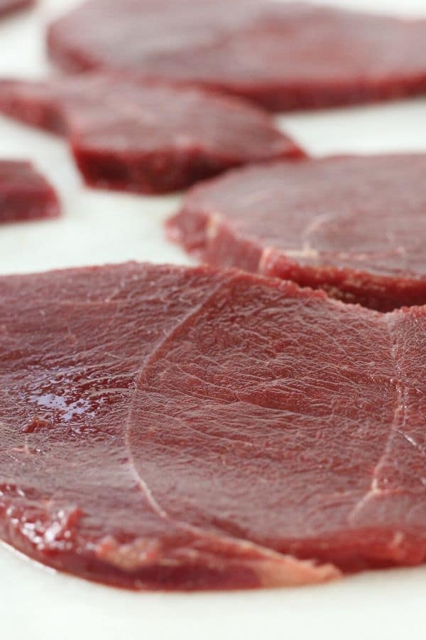 close up of deer meat sliced on cutting board 