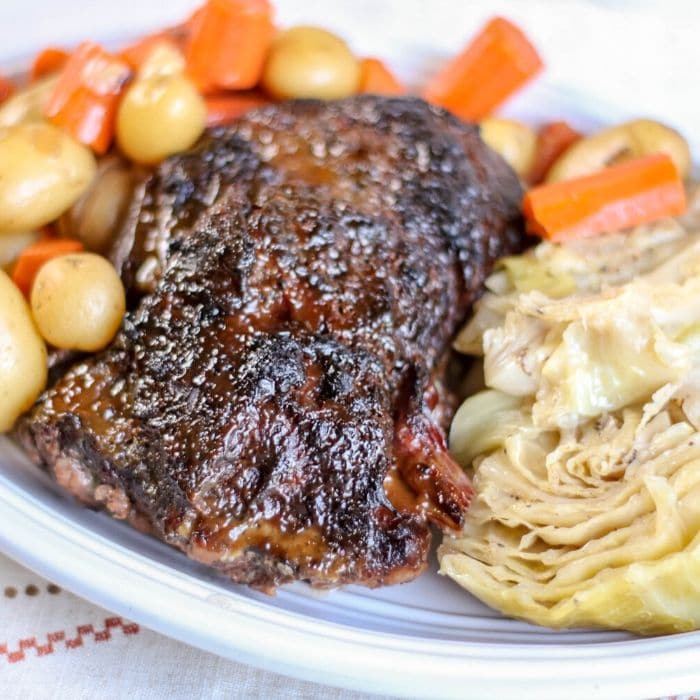 glazed corned beef, cabbage and vegetables sitting on a plate on table 