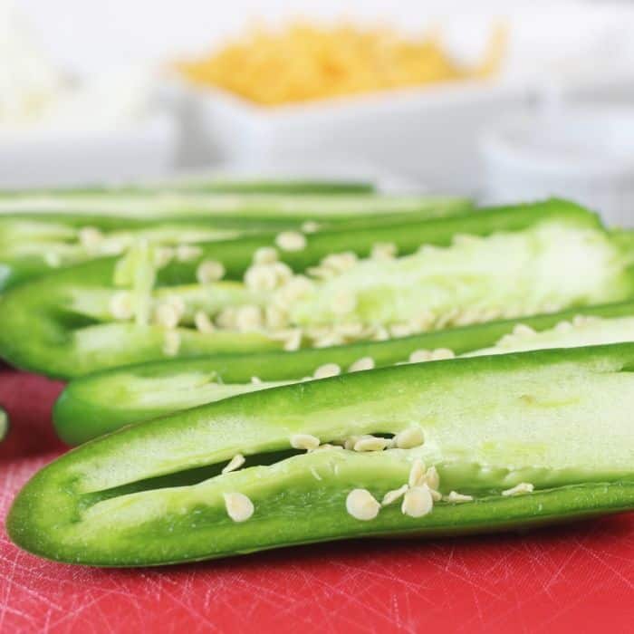 sliced jalapenos on a red cutting board 