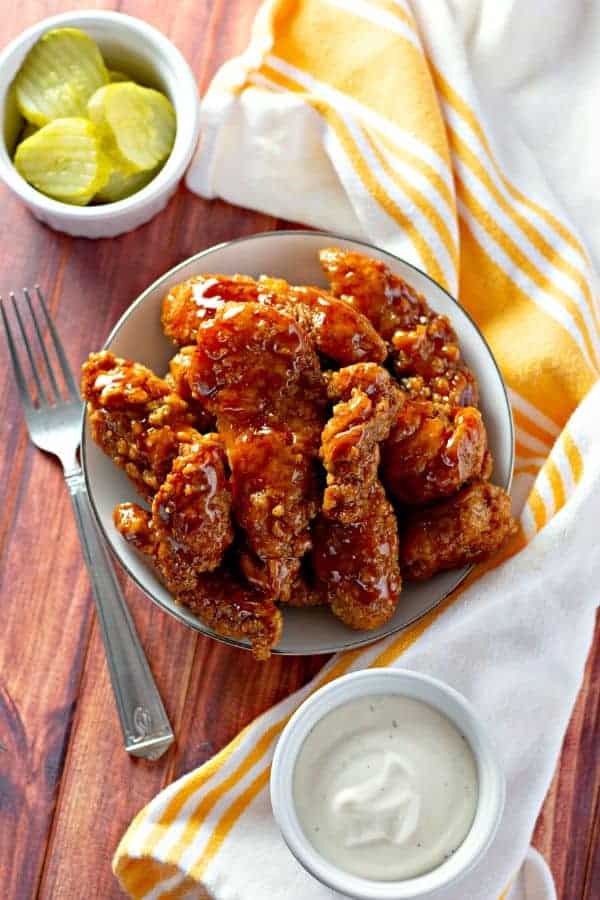 air fryer chicken strips on a plate with pickles by it 