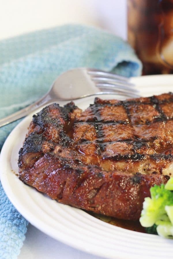 seasoned steak on a plate with fork by it 