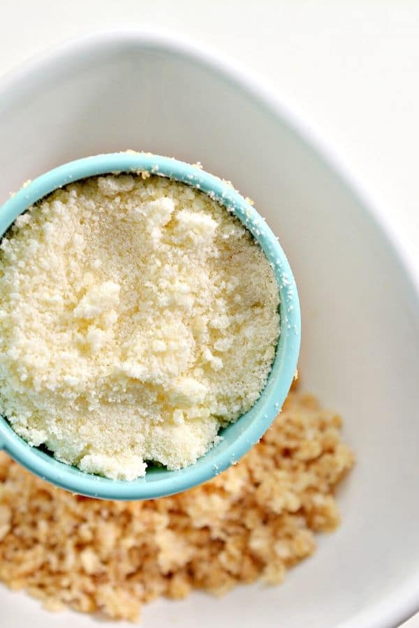 parmesan in a measuring cup being dumped into a bowl 