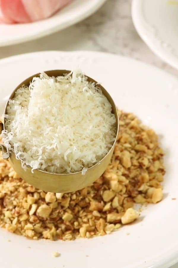 dumping parmesan cheese on top of crushed almonds in a plate 