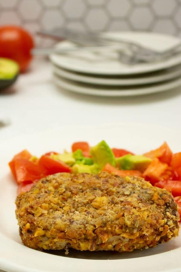 pork chop on plate with veggies behind it 