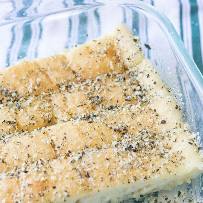 breadsticks in a glass pan with towel behind it 