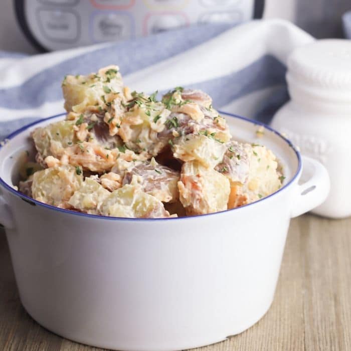 cheddar potato salad in a white and blue bowl 