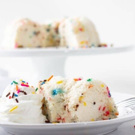 angel food cake with sprinkles on a plate with cake pan behind it