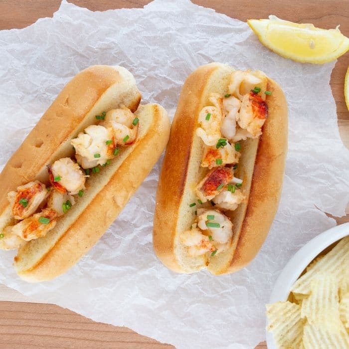 2 lobster rolls on table with chips