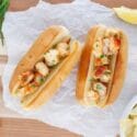 lobster rolls with lemons and chips beside it