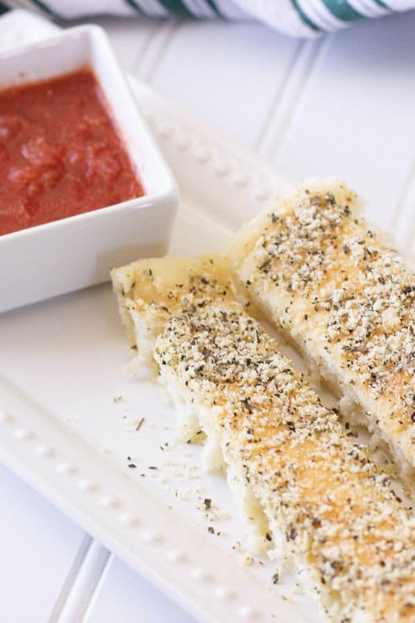 pizza breadsticks on tray with sauce by it 