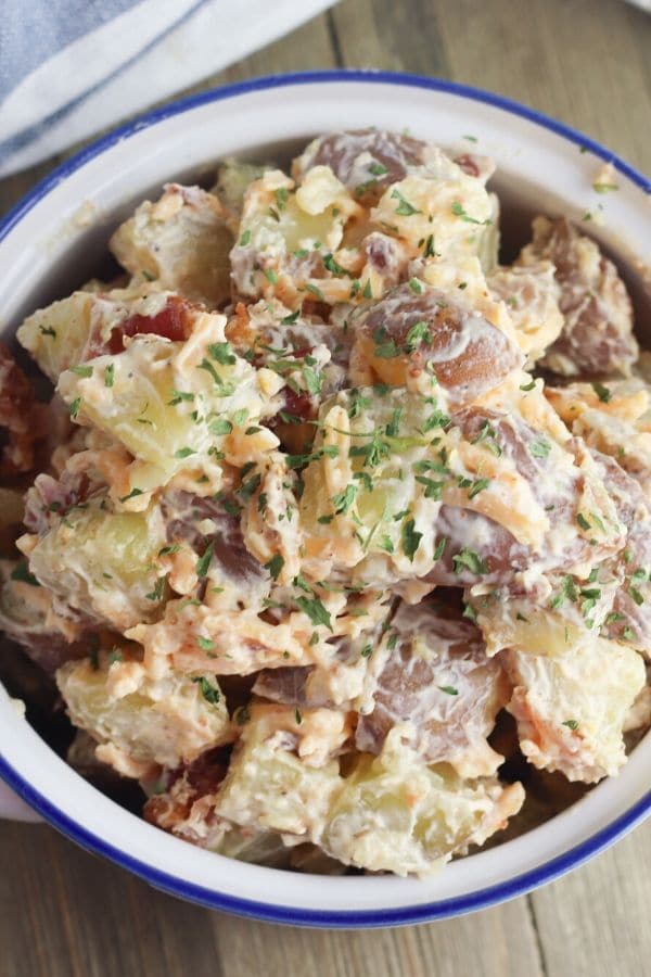 potato salad in a white bowl with blue line around it 