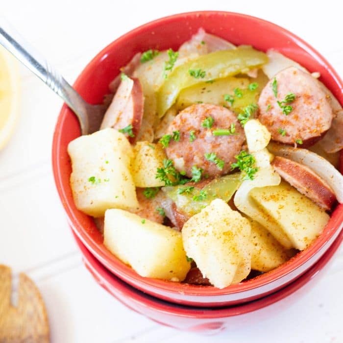 potatoes and sausage in a red bowl with fork