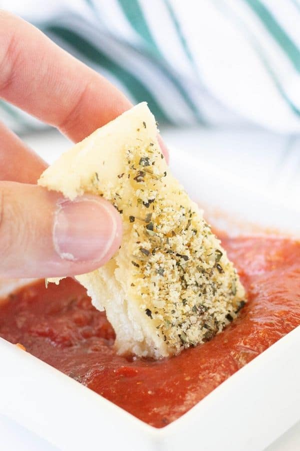 breadstick being dipped into a marinara sauce 