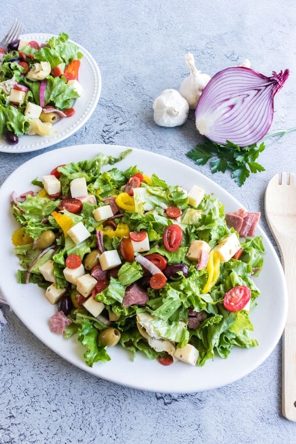 antipasto salad on a platter and plate behind it 