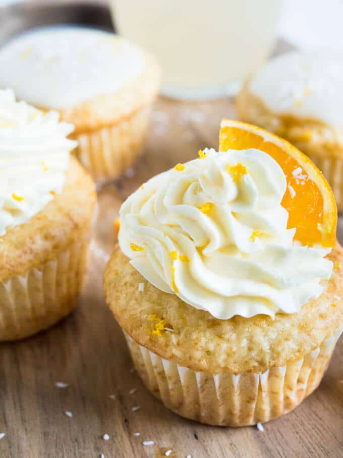 orange cupcake with a orange slice on top of frosting on wooden table 