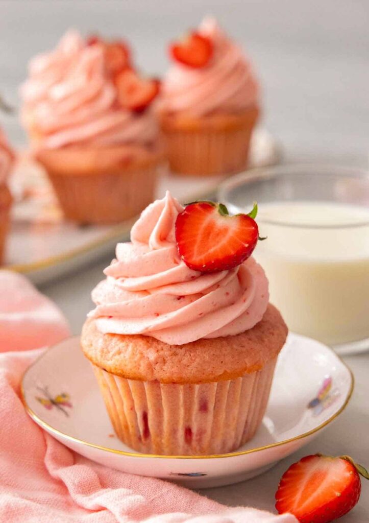 plate with a strawberry cupcake topped with a fresh sliced strawberry