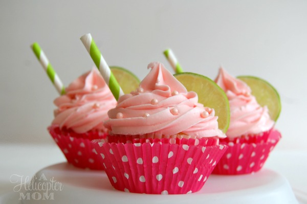 strawberry margarita cupcakes with straw sticking out on sides on a cupcake stand 