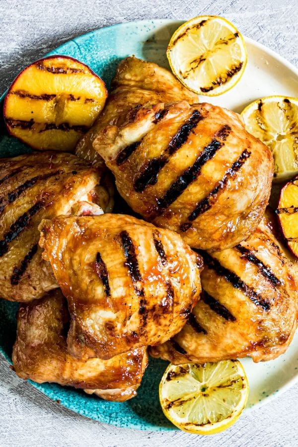 peach bbq chicken on a blue plate piled up