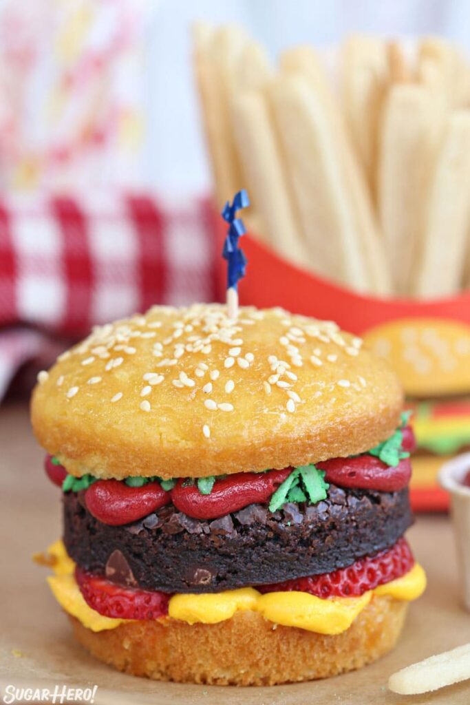 hamburger decorated cupcakes with dessert fries behind it on table 