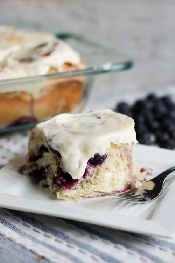 blueberry roll on a plate with berries i the background 