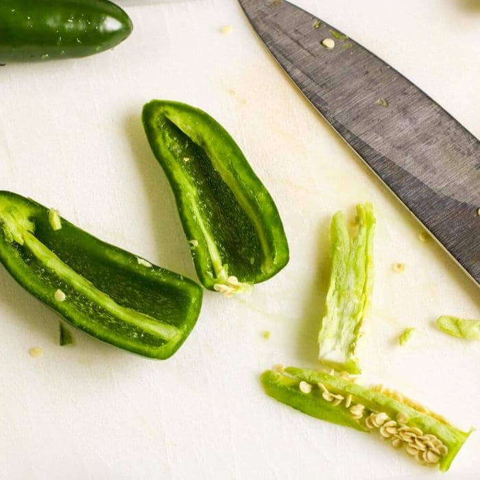 prepping jalapenos on white cutting board