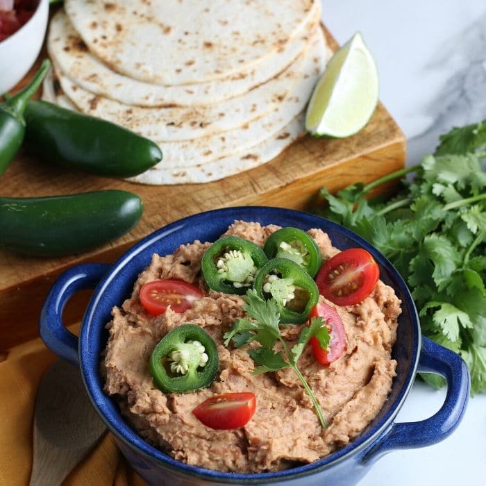 refried beans in a bowl with tortillas by it 