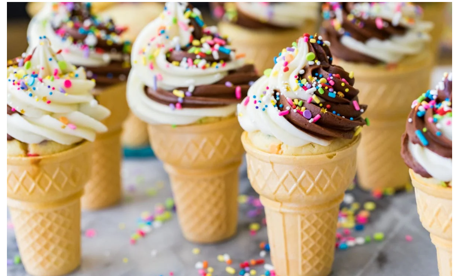 ice cream cone cupcakes sitting on table with sprinkles scattered on marble table 