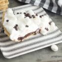 s'mores pie slice on a plate with black and white towel behind