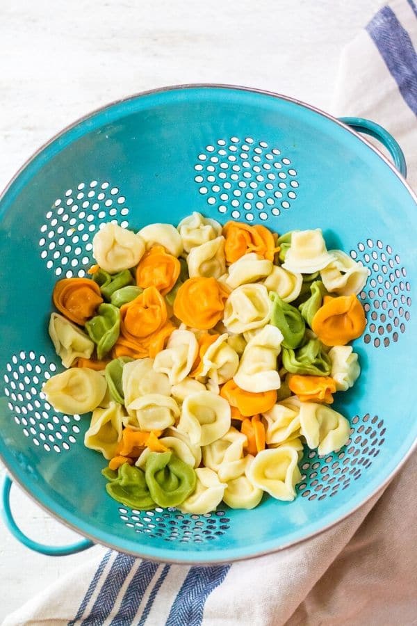 cooked tortellini drained in a colander on table