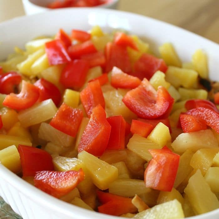 baking dish with pineapple and red peppers on top of chicken