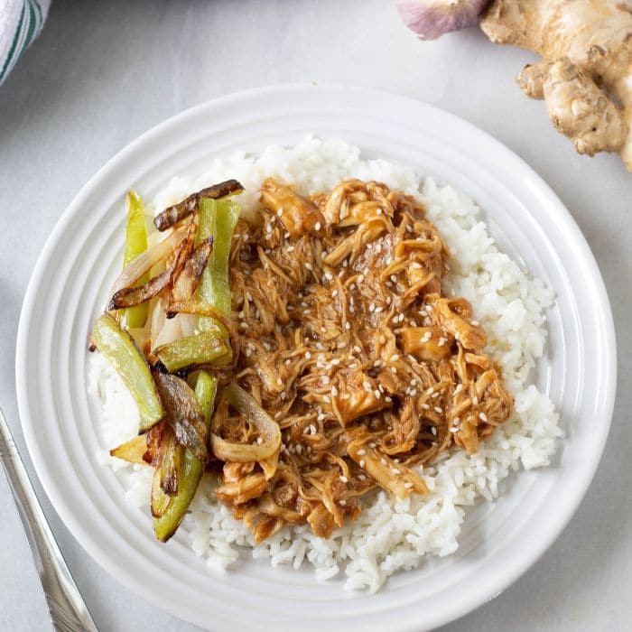 chicken teriyaki on a plate with a bed of rice 