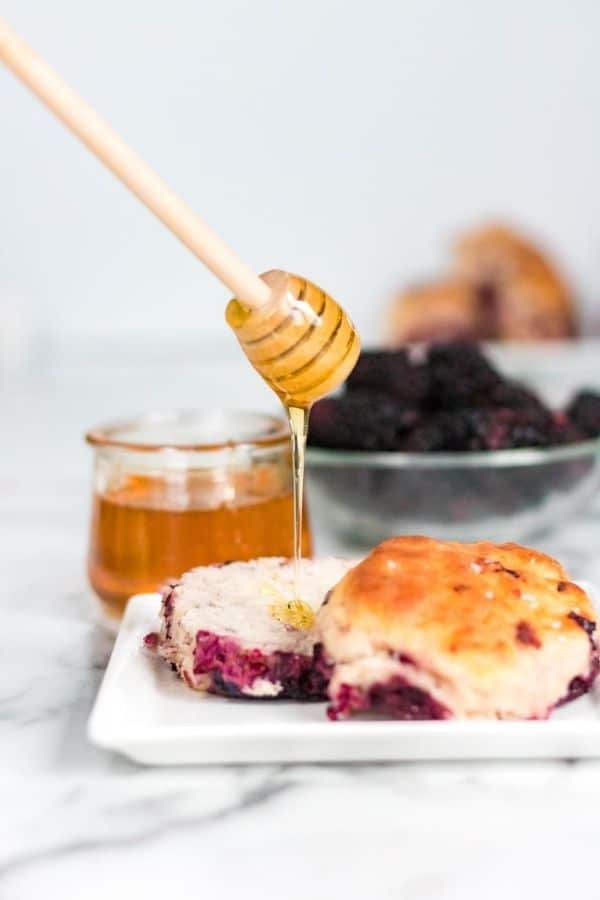 honey being drizzled over blackberry biscuit 