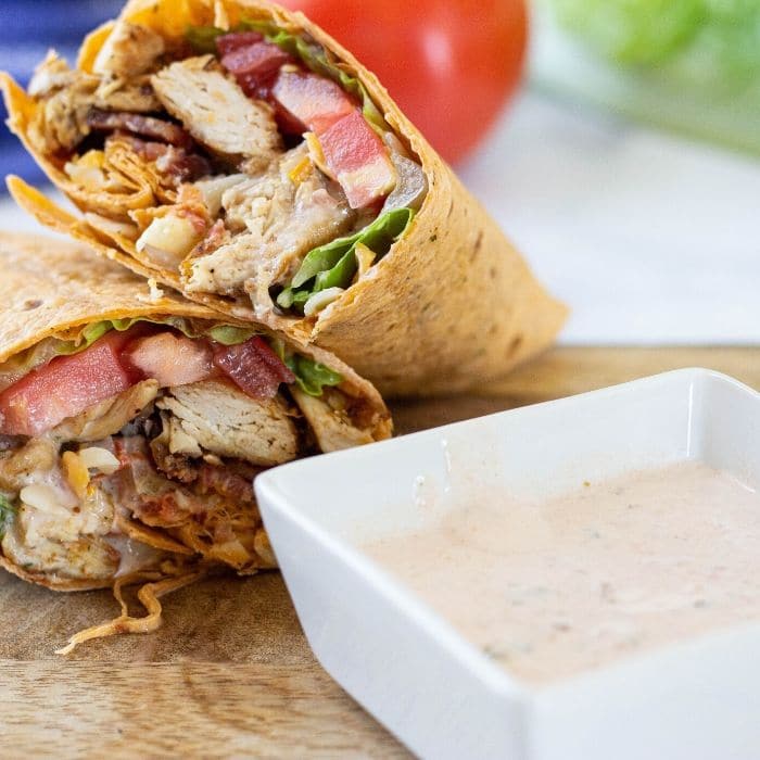 chicken wrap on wooden board with bowl of mexi-ranch