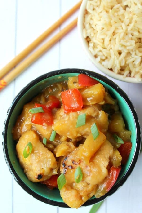 Hawaiian chicken in a bowl with rice behind it and chopsticks