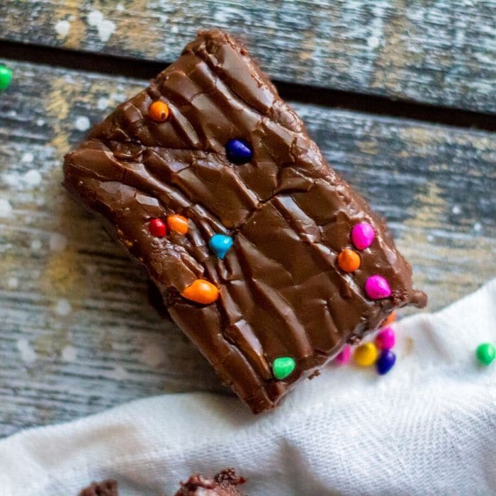 a cosmic brownie on table with sprinkles by it and towel 