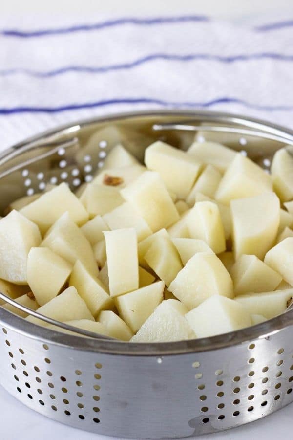 Diced raw potatoes in a steamer basket 