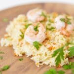 rice pilaf with shrimp on top on a wooden plate