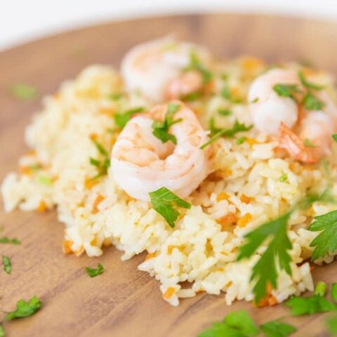 rice pilaf with shrimp on top on a wooden plate