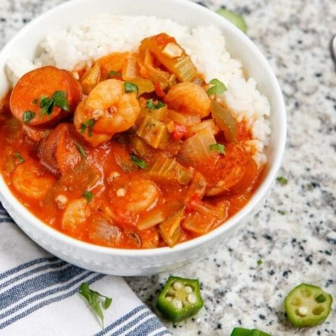 shrimp gumbo in a bowl with rice and a spoon by it on table