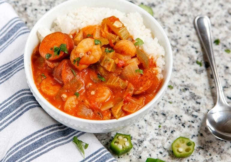 shrimp gumbo in a bowl with rice and a spoon by it on table