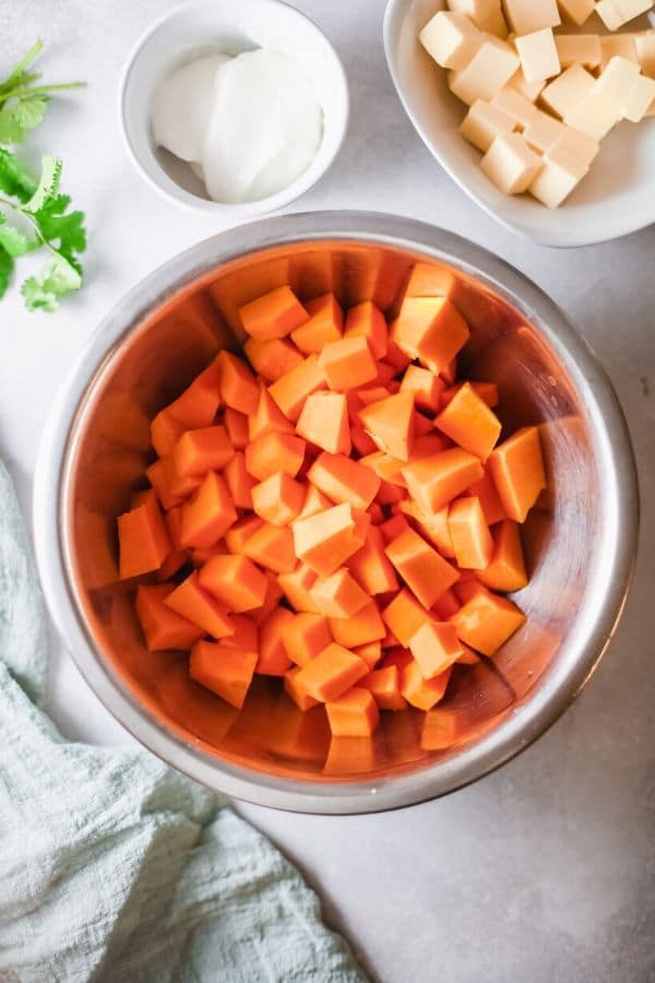 cubed sweet potatoes in a bowl with butter and sour cream by it 