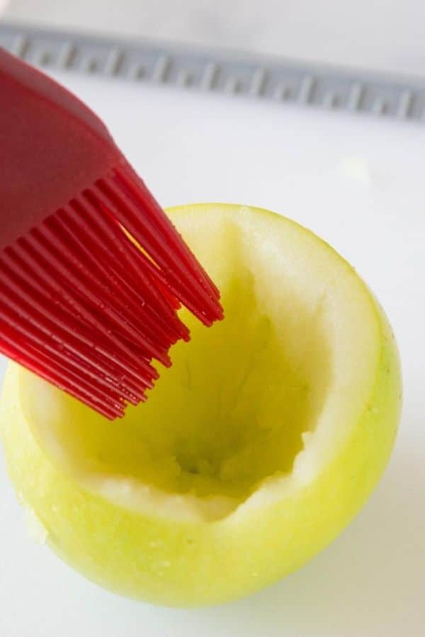 cored apple being brushed with lemon juice 