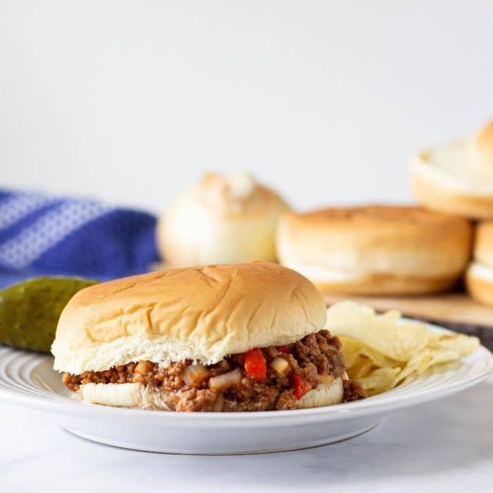 sloppy joe on a plate with chips and a pickle