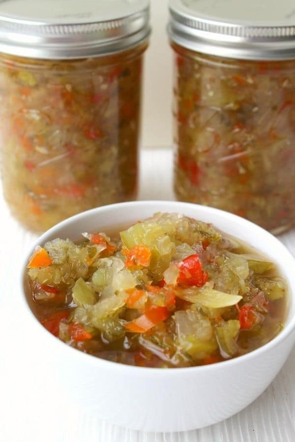 sweet relish in a white bowl with jars behind it 